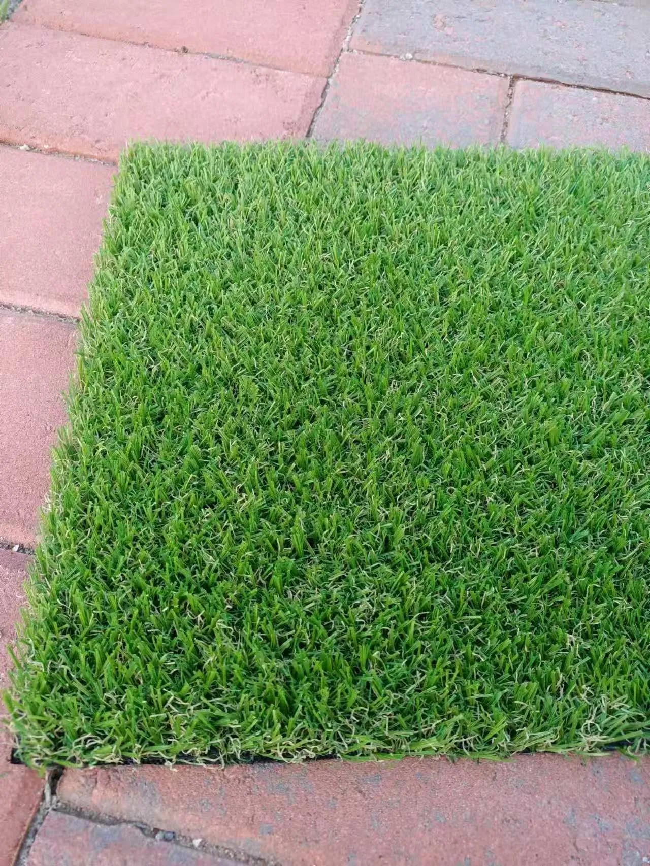 20mm short-pile artificial turf sample shown on brick pavers