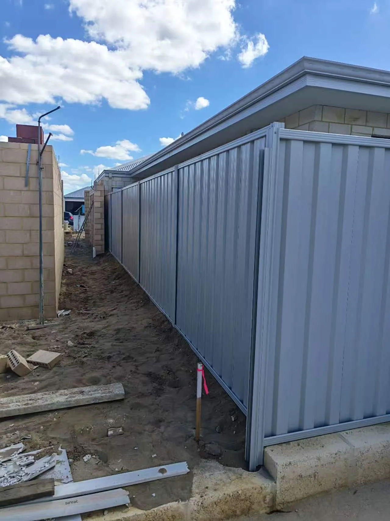Newly installed grey Colorbond boundary fence with a corner return on a new-build site