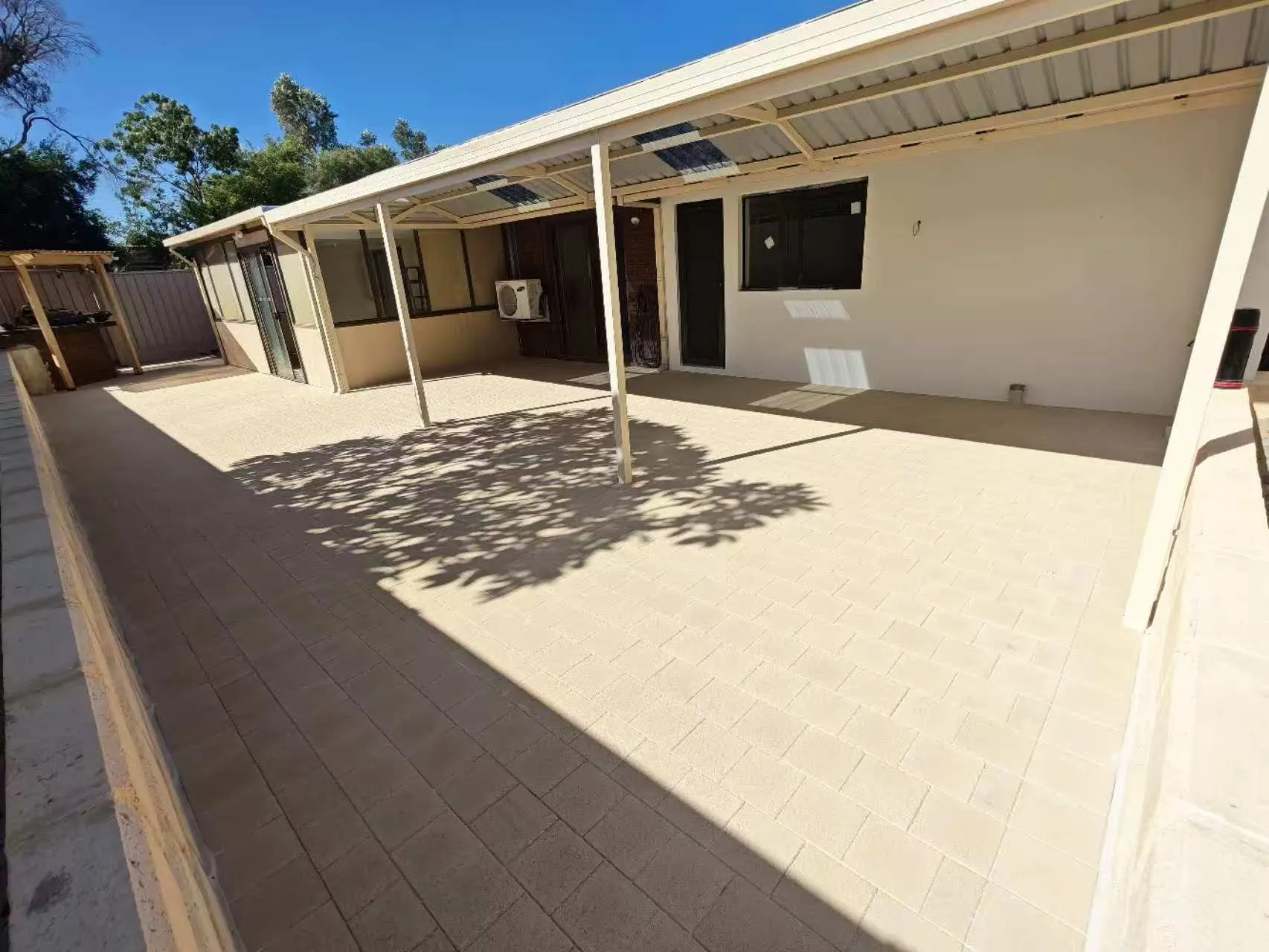 Freshly paved entry forecourt beneath a home's alfresco and portico