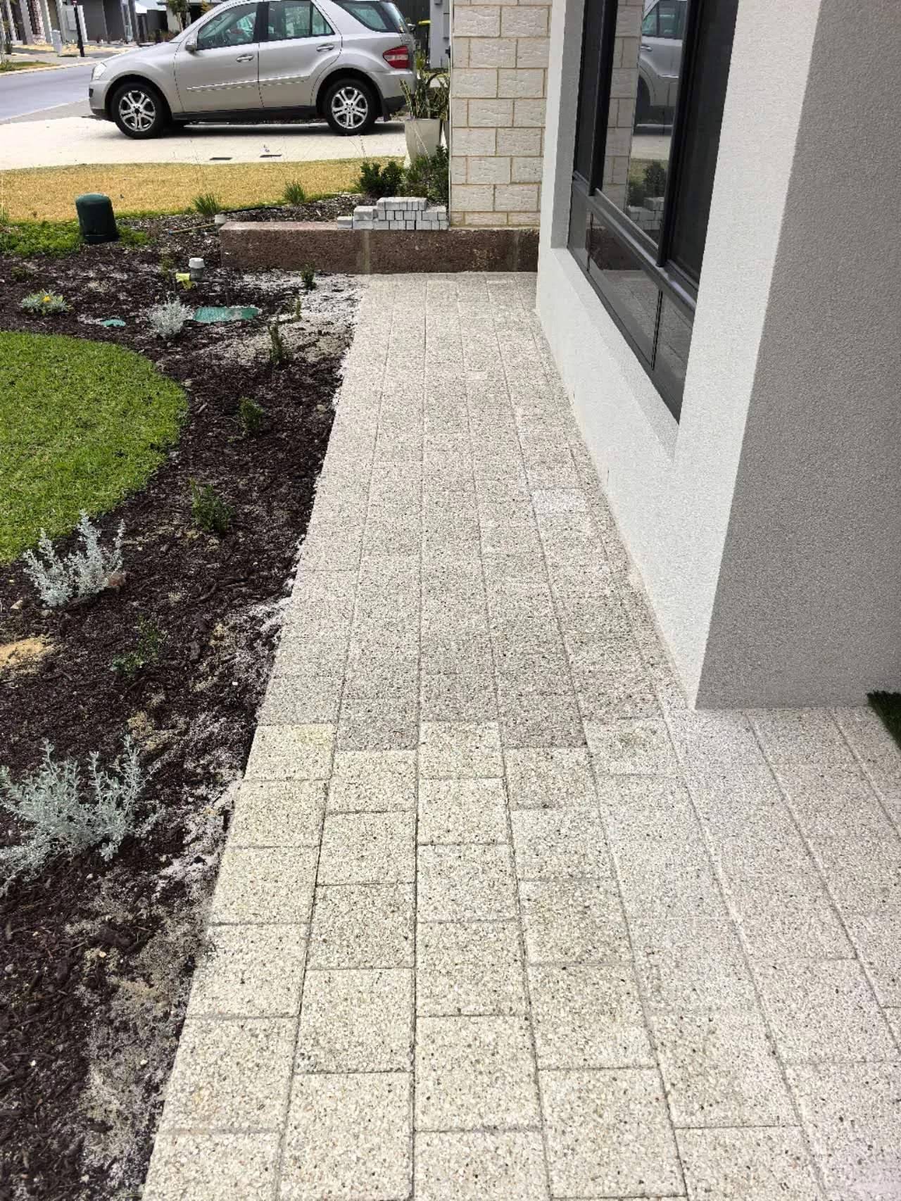 Front entry path in granite-look pavers with a cobbled border, beside planted garden beds