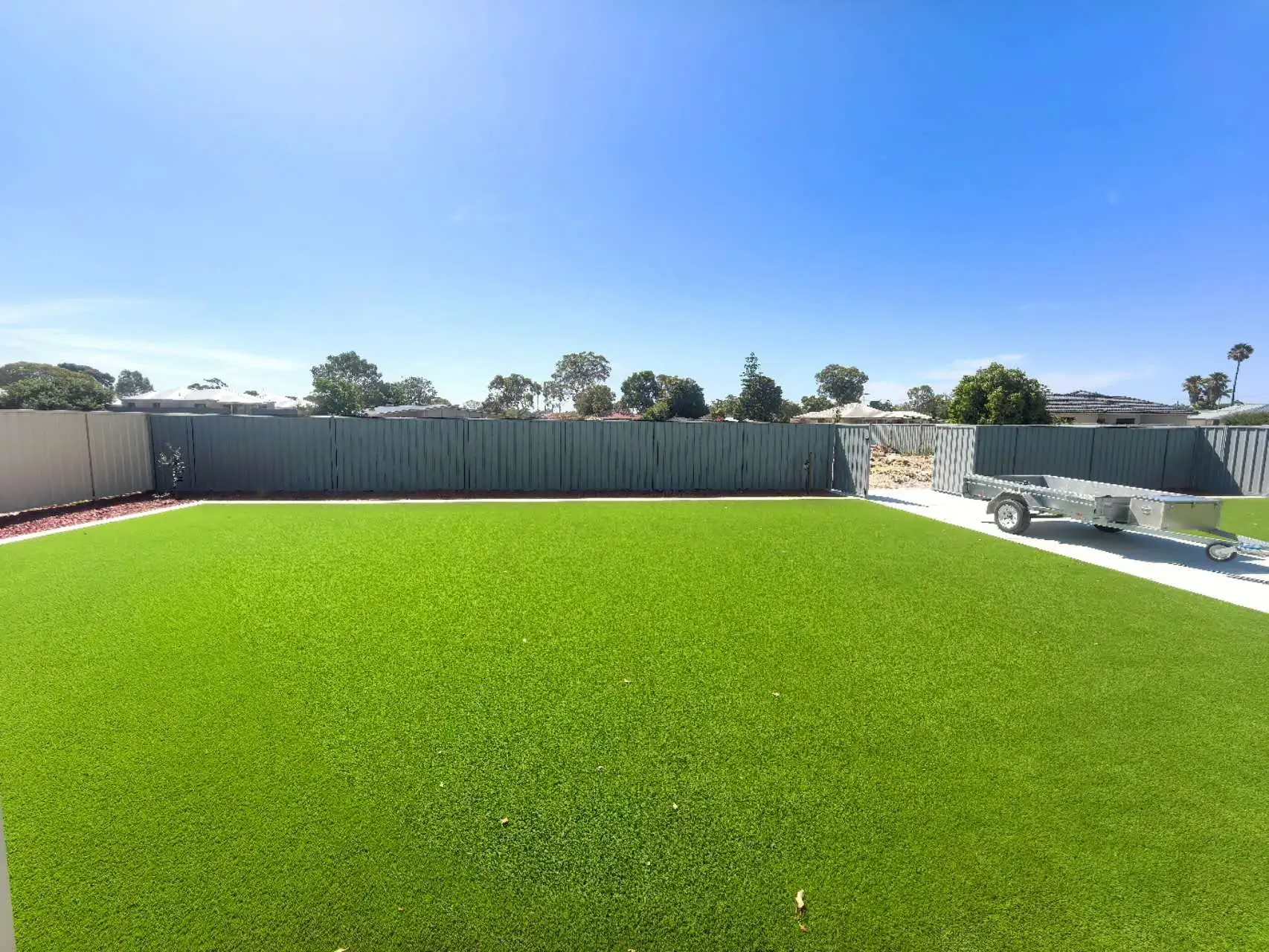Large lush artificial grass lawn with new grey Colorbond fencing across a full backyard